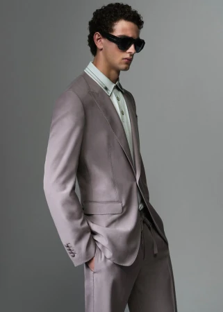 Model wearing a tailored taupe suit jacket and sunglasses against a grey backdrop for Dolce & Gabbana Mens S/S 26
