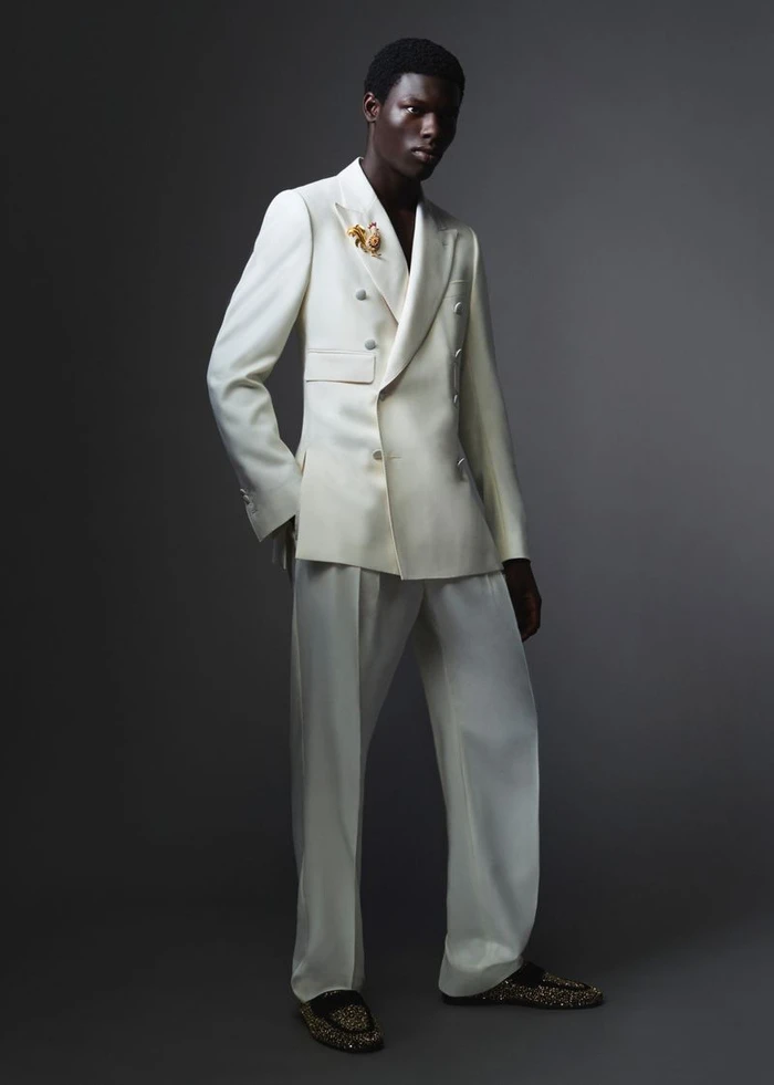 Black man wearing a white double-breasted suit against a dark grey studio background for Dolce and Gabbana Mens S/S 26
