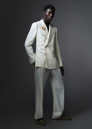 Black man wearing a white double-breasted suit against a dark grey studio background for Dolce and Gabbana Mens S/S 26