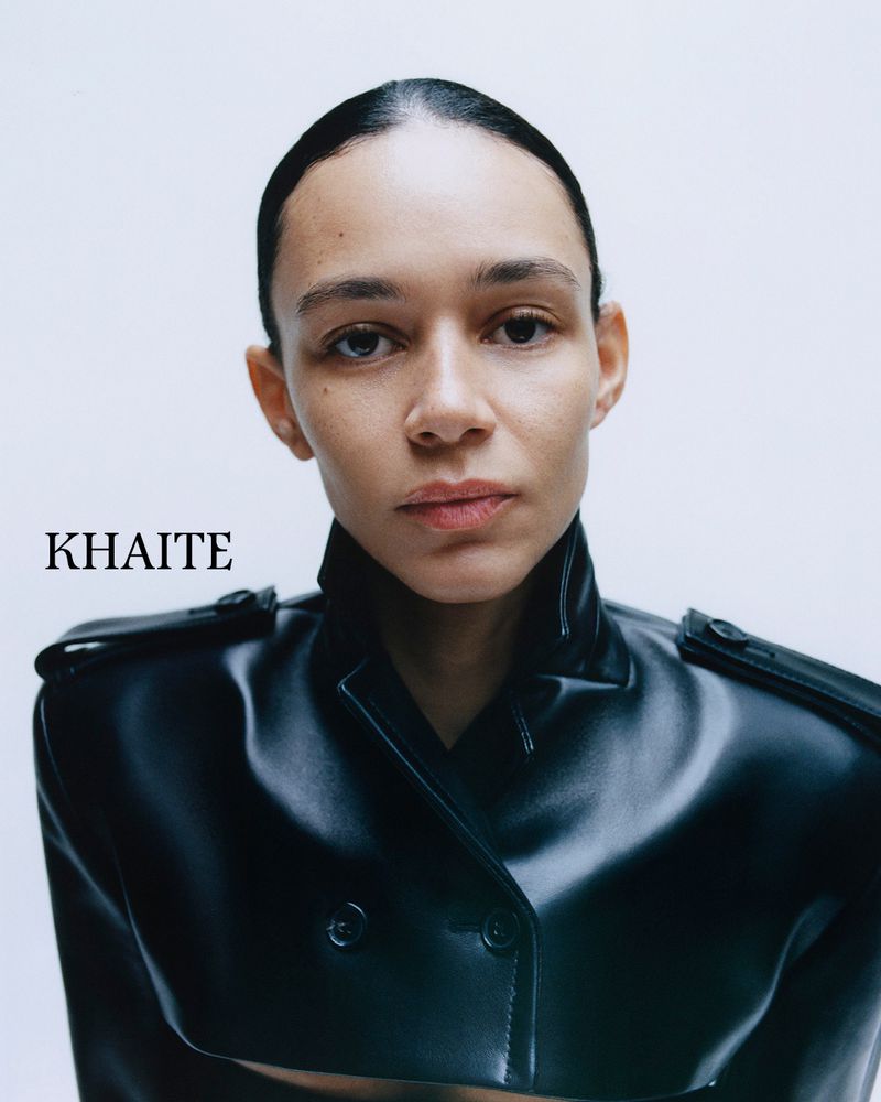 Close-up portrait of model Binx Walton wearing a black leather jacket against a white background for Khaite S/S 2026.