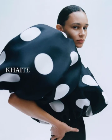 Model Binx Walton wearing a black and white polka dot sculptural top for Khaite S/S 2026 against a plain background