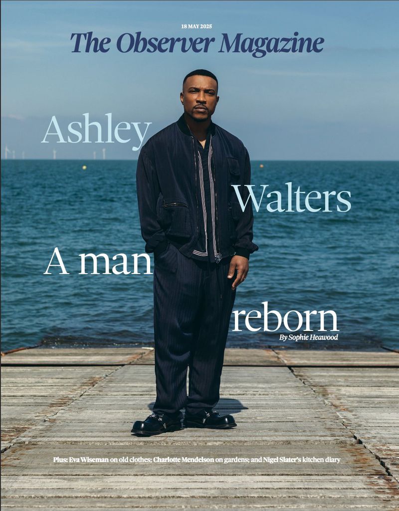 Magazine cover featuring Ashley Walters on a wooden dock with the sea in the background, wearing a navy jacket and pants.