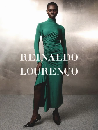Model wearing a long-sleeved green dress standing against a textured metallic background with text overlay