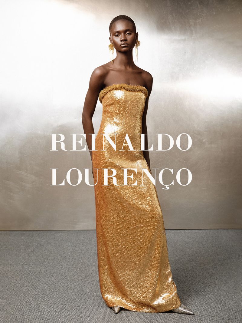 Model in a metallic gold strapless sequined gown against a textured silver background, photographed by Higor Bastos.
