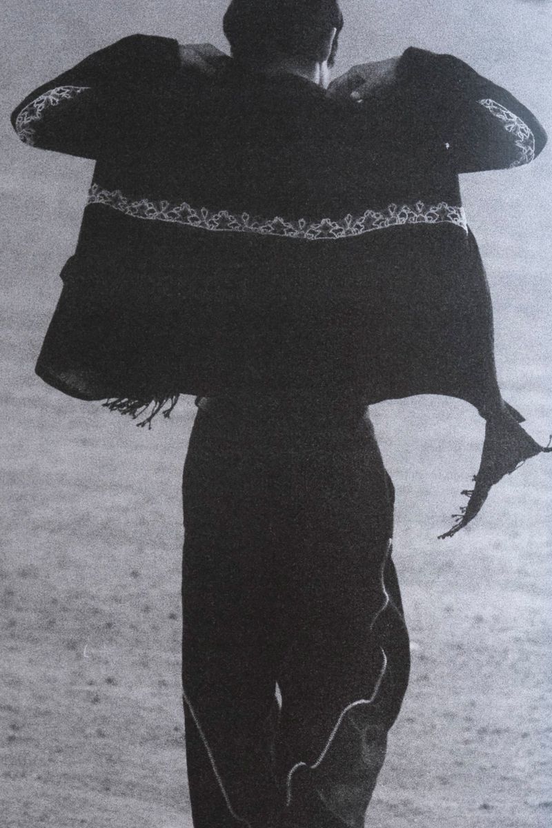 Rear view of a model wearing an embroidered dark jacket and trousers for Kartik Research S/S 26 campaign