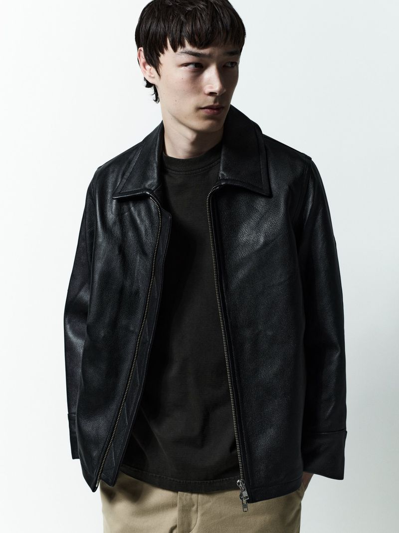 Model in black leather jacket and dark t-shirt against a plain white studio background for AGOLDE Man.