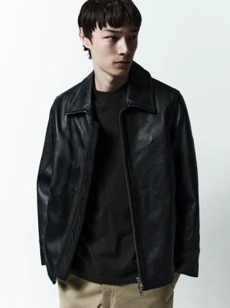 Model in black leather jacket and dark t-shirt against a plain white studio background for AGOLDE Man.