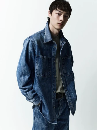 Model Pascal Thulin in a blue denim shirt and matching pants against a white background for AGOLDE Man.