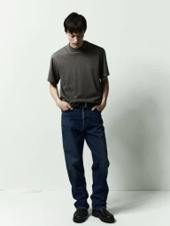Model wearing a dark grey t-shirt and blue denim jeans against a plain white studio background.
