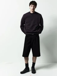 Model wearing dark sweatshirt and black shorts against a white background