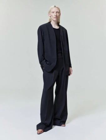 Model Maggie Maurer wearing a dark oversized blazer and trousers against a neutral studio backdrop