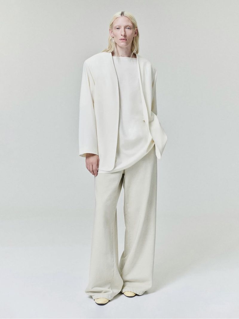 Model Maggie Maurer wearing an off-white blazer and matching trousers against a white seamless background for Fear of God.