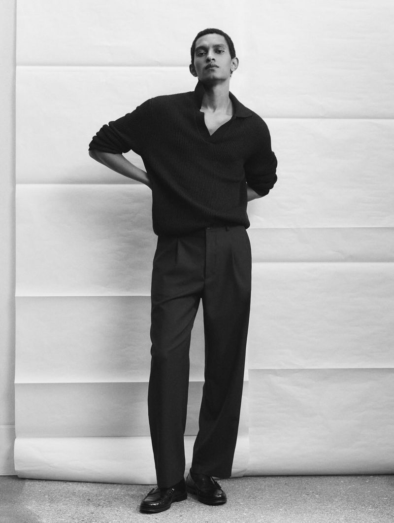 Monochrome fashion editorial image of a male model posing against a white seamless paper backdrop.