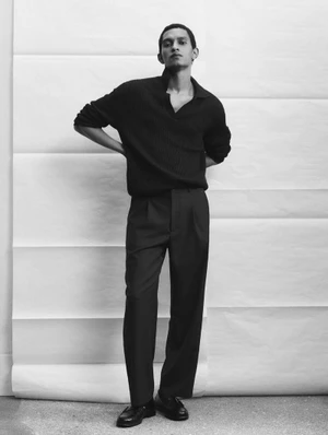 Monochrome fashion editorial image of a male model posing against a white seamless paper backdrop.