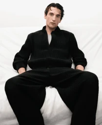 Model Anatol Modzelewski wearing a black ribbed zip cardigan and matching pants against a plain white backdrop.