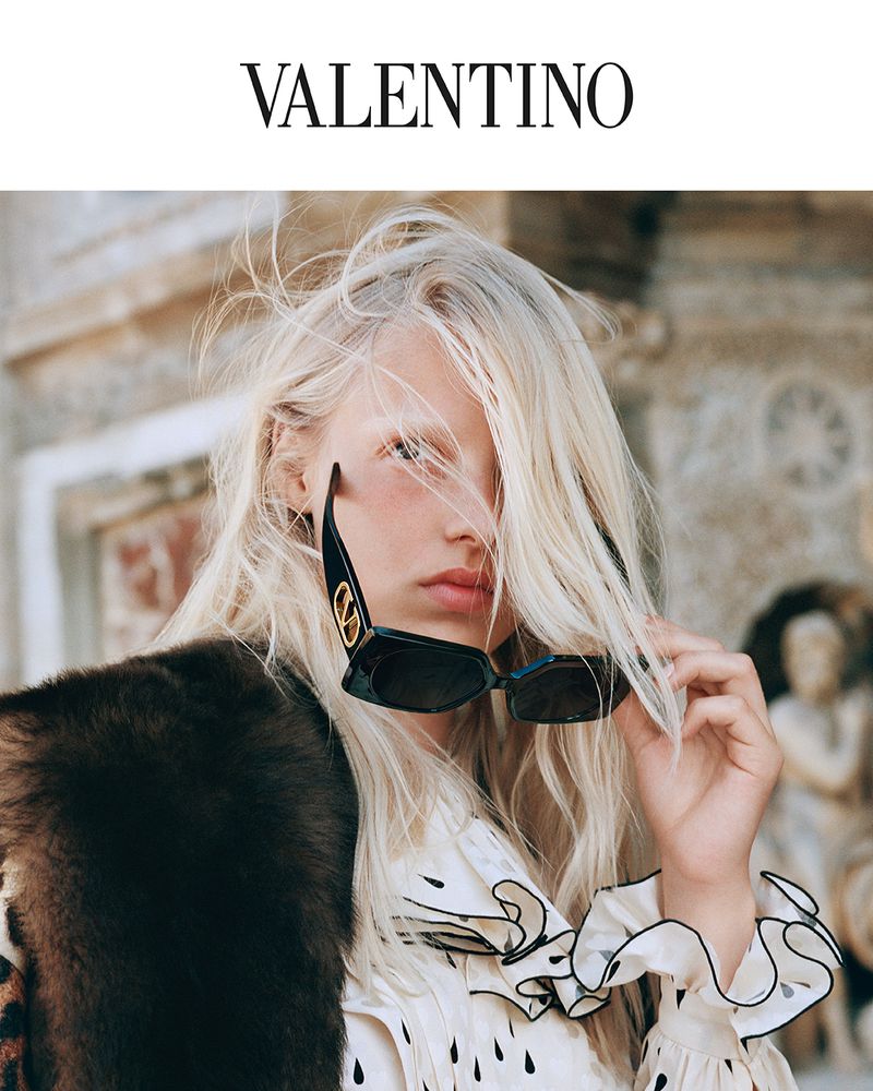 Model with long blonde hair wearing black sunglasses and ruffled blouse for Valentino eyewear campaign