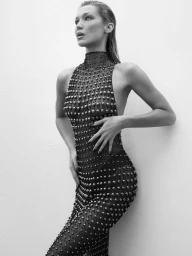 Bella Hadid in a black embellished sleeveless dress with wet-look hair against a seamless white background for Revolve