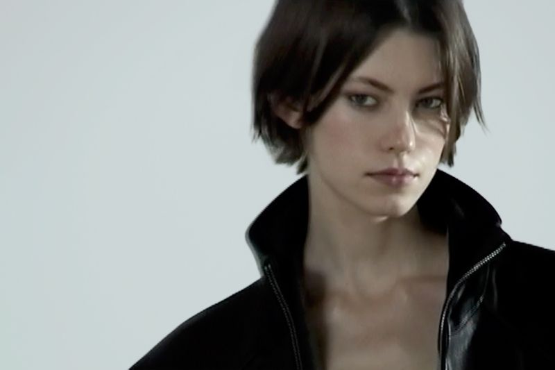 Portrait of a model wearing a black zippered jacket against a plain light background