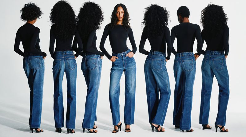Multiple views of a model wearing a black long-sleeve top and blue denim jeans against a white seamless background