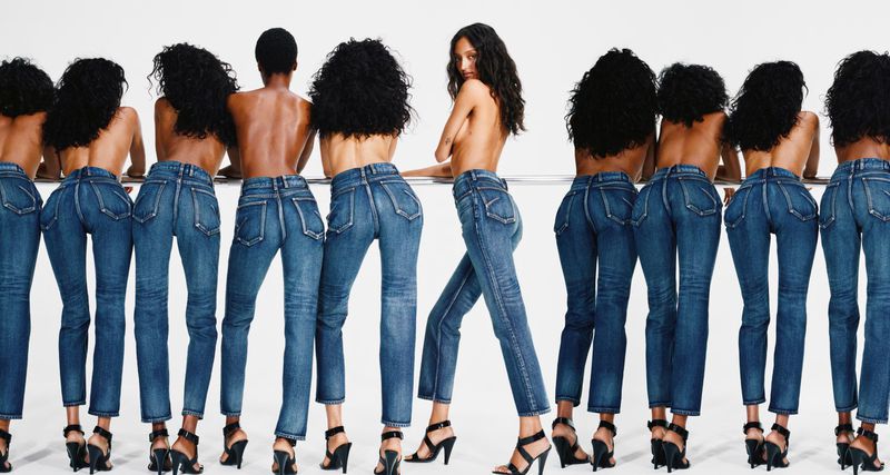 Multiple women wear blue jeans and black high heels in a studio shot. Fashion models pose to show off the fit of the denim clothing.