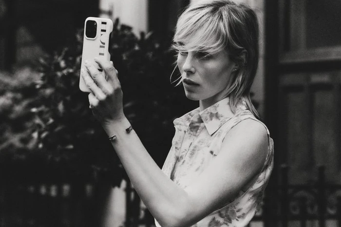 Edie Campbell taking a selfie with a smartphone for Carolina Herrera Matryoshka Pocket project, shot in black and white.