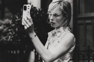 Edie Campbell taking a selfie with a smartphone for Carolina Herrera Matryoshka Pocket project, shot in black and white.
