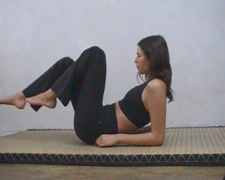 Model performing core exercises in black activewear on a mat against a plain wall for H&M Move Cotton Active