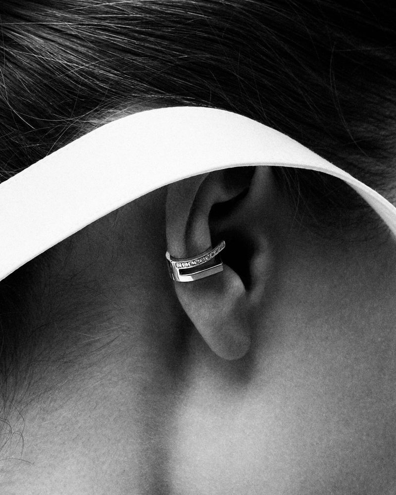 Close-up of an ear wearing a diamond ear cuff in a black and white portrait.