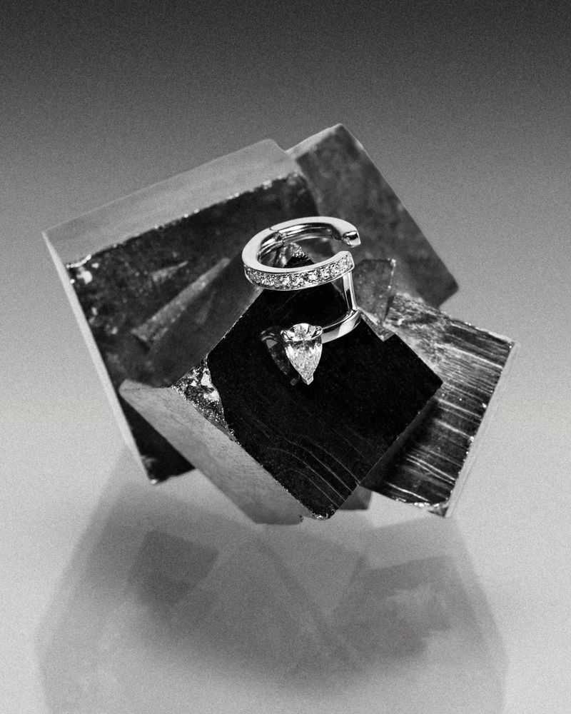 Repossi diamond ring resting on a faceted metallic mineral crystal under monochrome studio lighting.
