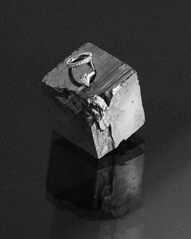 Diamond rings resting on a rough mineral cube against a dark background, photographed by Anouk Hart for Repossi.