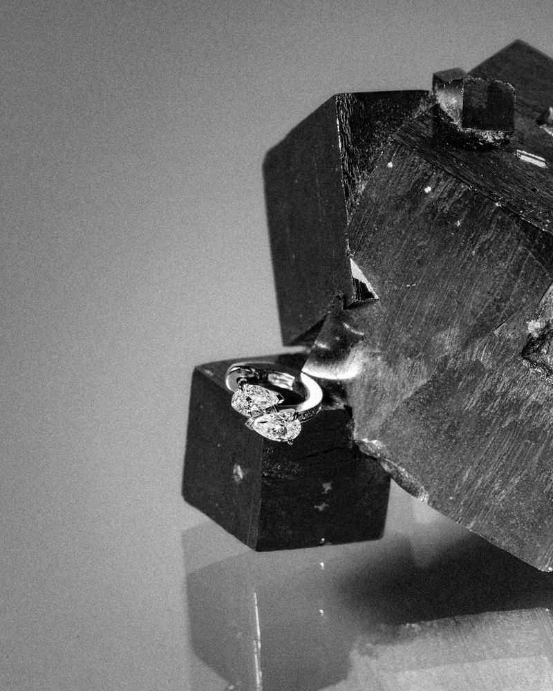 Close-up monochrome jewelry photograph of a Repossi diamond ring resting against dark crystal mineral formations.