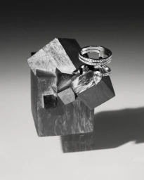 Close-up product shot of diamond rings resting on a crystalline mineral cluster against a gradient grey background