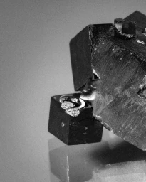 Close-up monochrome jewelry photograph of a Repossi diamond ring resting against dark crystal mineral formations.