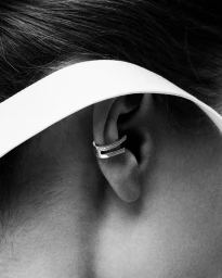 Close-up of an ear wearing a diamond ear cuff in a black and white portrait.