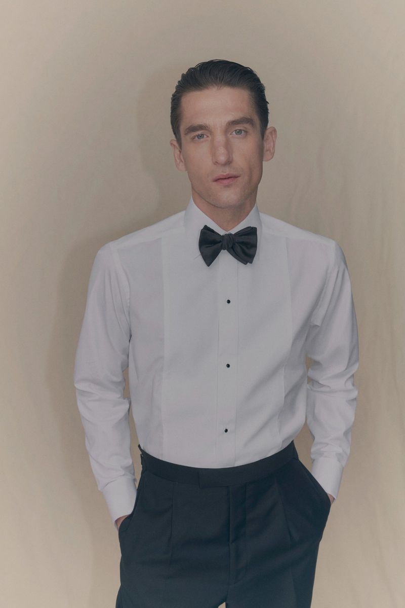 Man wearing a white dress shirt and black bowtie against a neutral backdrop for Eton of Sweden