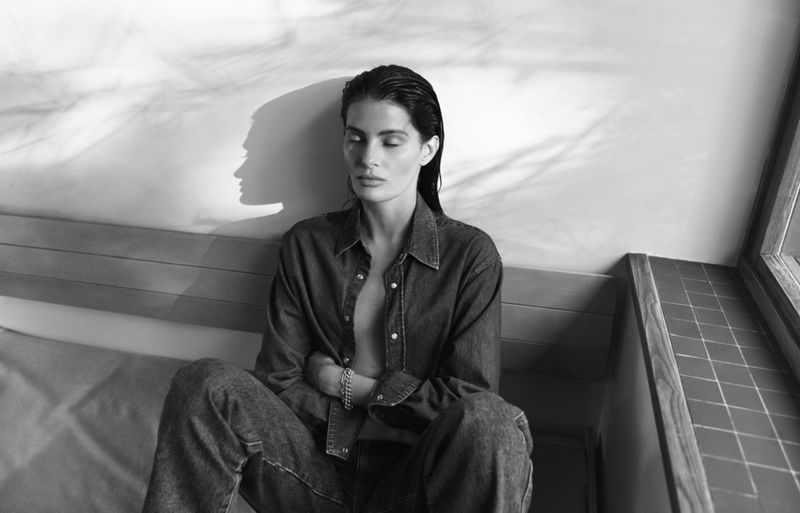 Model Isabeli Fontana wearing a denim shirt and jeans seated indoors for Matteau Summer 2026, photographed by Chris Colls.