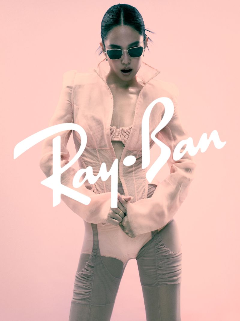 Jennie wearing dark sunglasses and a structured jacket against a pink background for Ray-Ban