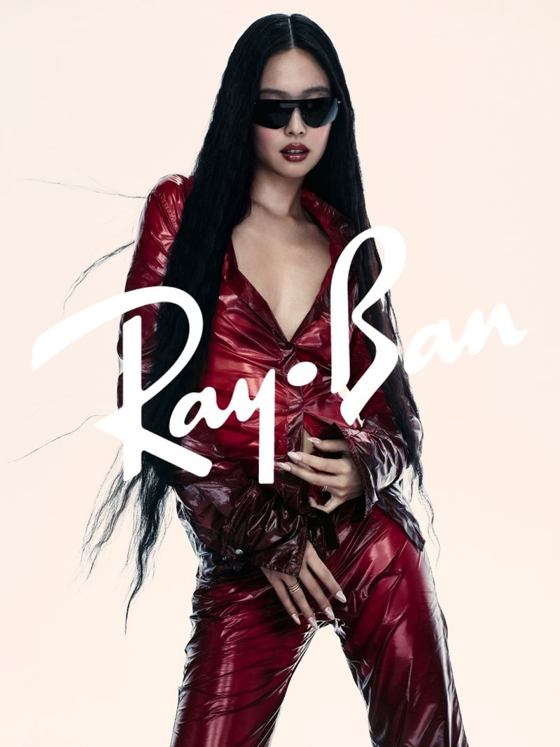 Jennie wearing dark sunglasses and a glossy red shirt and trousers against a pale background for Ray-Ban
