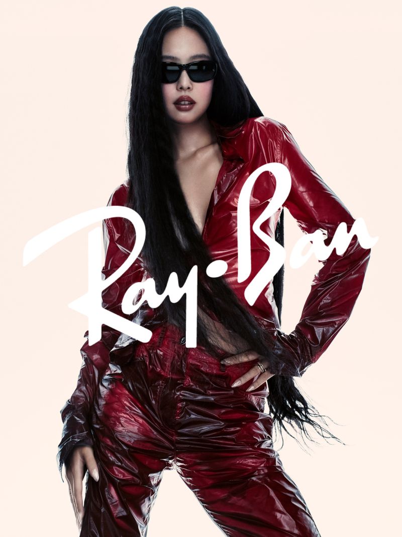 Jennie wearing black sunglasses and a red vinyl outfit against a pale background for Ray-Ban