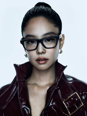 Jennie wearing black Ray-Ban glasses and a glossy burgundy jacket against a white background