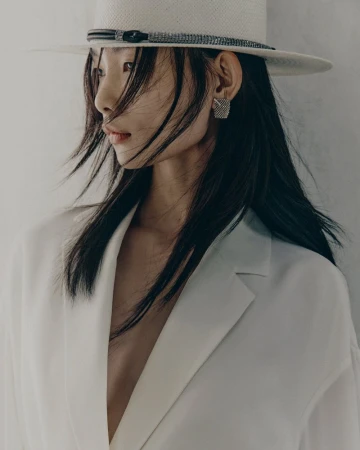 Model wearing a white fedora hat and white blazer against a neutral backdrop