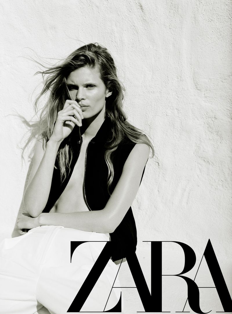 Model Ida Heiner leaning against a textured light wall in a black vest and white trousers for Zara Women March 2026.