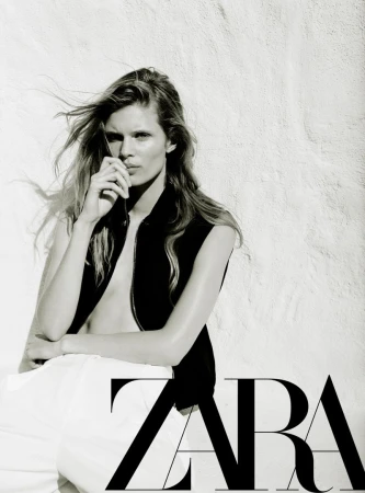 Model Ida Heiner leaning against a textured light wall in a black vest and white trousers for Zara Women March 2026.