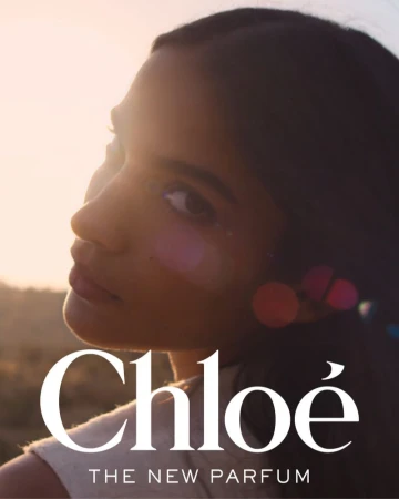 Close-up portrait of a young adult woman with dark hair, in profile, with blurred background and Chloe brand logo, 'The New Parfum' text.