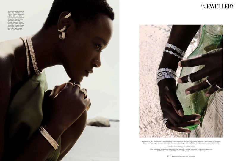 Model wearing gold and silver jewelry including layered necklaces, multiple ear cuffs, and rings outdoors by water.