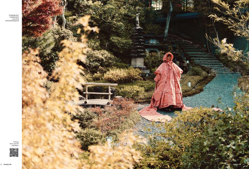 Model in voluminous pink dress standing in Japanese garden with stone pagoda and pathway