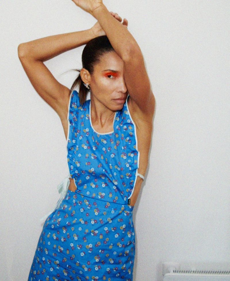 Model in blue floral dress with arms raised against a plain white background for M Le magazine du Monde