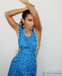 Model in blue floral dress with arms raised against a plain white background for M Le magazine du Monde