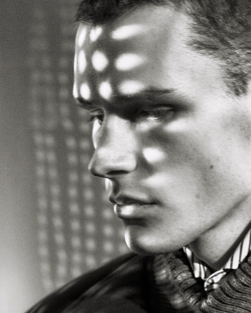 Monochrome portrait of a male model with distinctive patterned light cast across his forehead and face