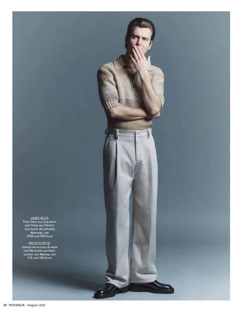 Full-length portrait of a male model wearing a knit polo shirt and light trousers against a grey seamless background